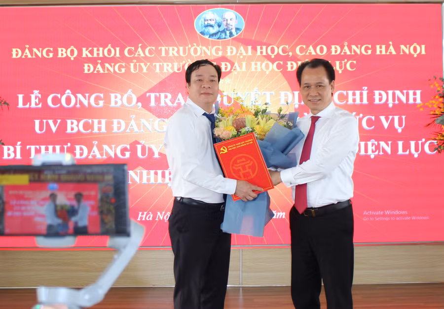 Ông Nguyễn Thanh Sơn - Bí thư Đảng ủy Khối các trường ĐH CĐ Hà Nội (bên phải) trao quyết định và chúc mừng tân Bí thư Đảng ủy trường Đại học Điện lực.