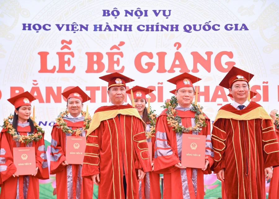 Thứ trưởng Bộ Nội vụ Triệu Văn Cường (bên trái) và Giám đốc Học viện Hành chính Quốc gia (bên phải) trao bằng cho các Tiến sĩ tại lễ bế giảng.