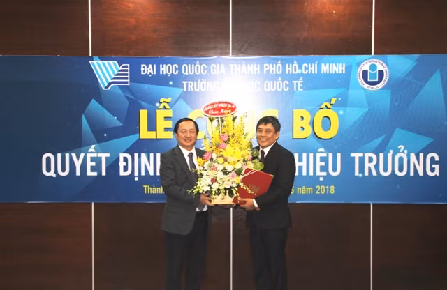  PGS.TS Huỳnh Thành Đạt - Giám đốc ĐHQG TPHCM trao quyết định và tặng hoa chúc mừng TS. Trần Tiến Khoa (phải)