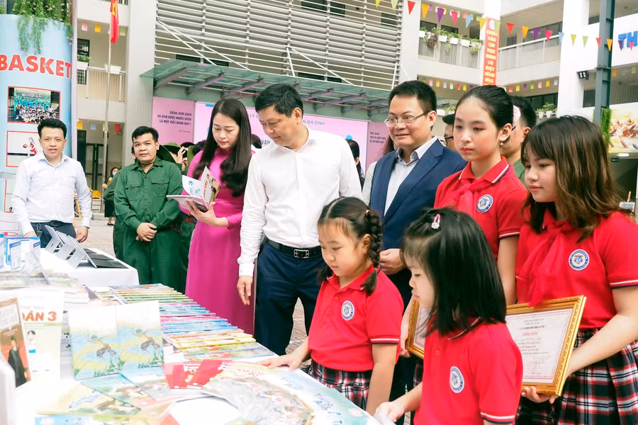 Đại biểu và các em học sinh thăm quan gian trưng bày sách. 