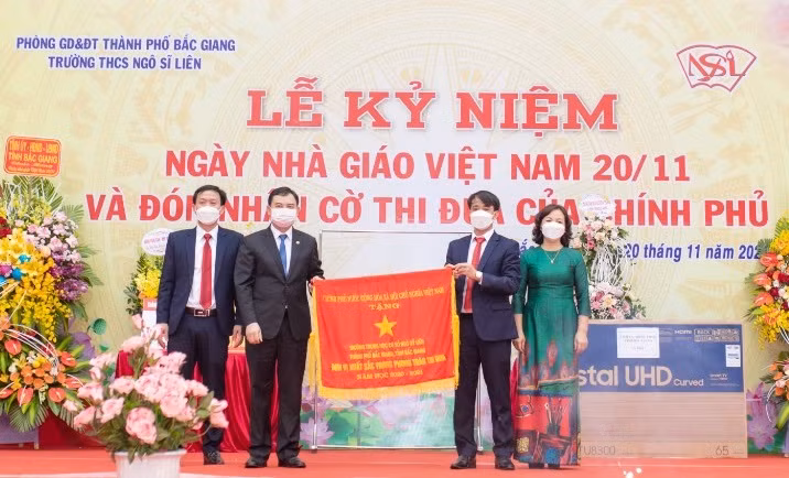 Thừa ủy quyền, ông Vũ Trí Hải, Ủy viên BTV Tỉnh ủy Bắc Giang, Bí thư Thành ủy Bắc Giang (thứ 2 từ trái sang) trao Cờ thi đua của Chính phủ cho Trường THCS Ngô Sĩ Liên.