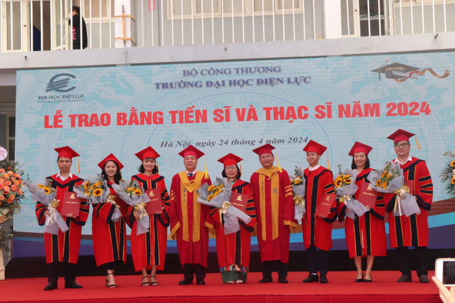 PGS.TS Vũ Đình Ngọ - Chủ tịch Hội đồng trường (bên trái) và PGS.TS Đinh Văn Châu - Hiệu trưởng trường Đại học Điện lực trao bằng, chúc mừng các tân Tiến sĩ.