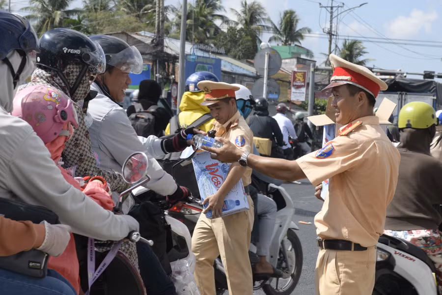 Cán bộ Phòng CSGT Công an tỉnh Tiền Giang trao tặng nước uống cho người dân về quê sáng 28/4.