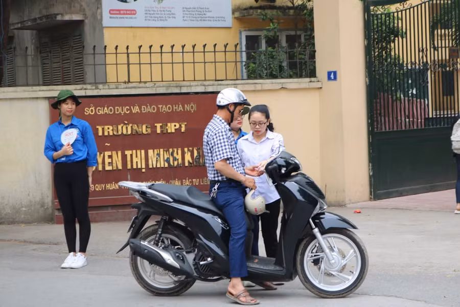 Một phụ huynh động viên con chuẩn bị, kiểm tra kỹ các vật dụng, giấy tờ cần thiết trước khi bước vào phòng thi trước giờ vào thi.