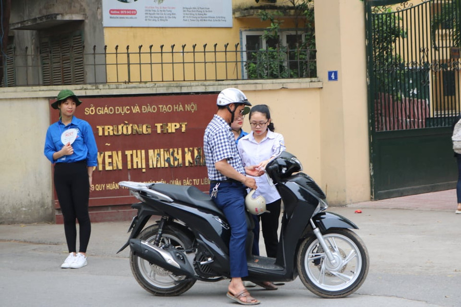 Một phụ huynh động viên con chuẩn bị, kiểm tra kỹ các vật dụng, giấy tờ cần thiết trước khi bước vào phòng thi trước giờ vào thi.