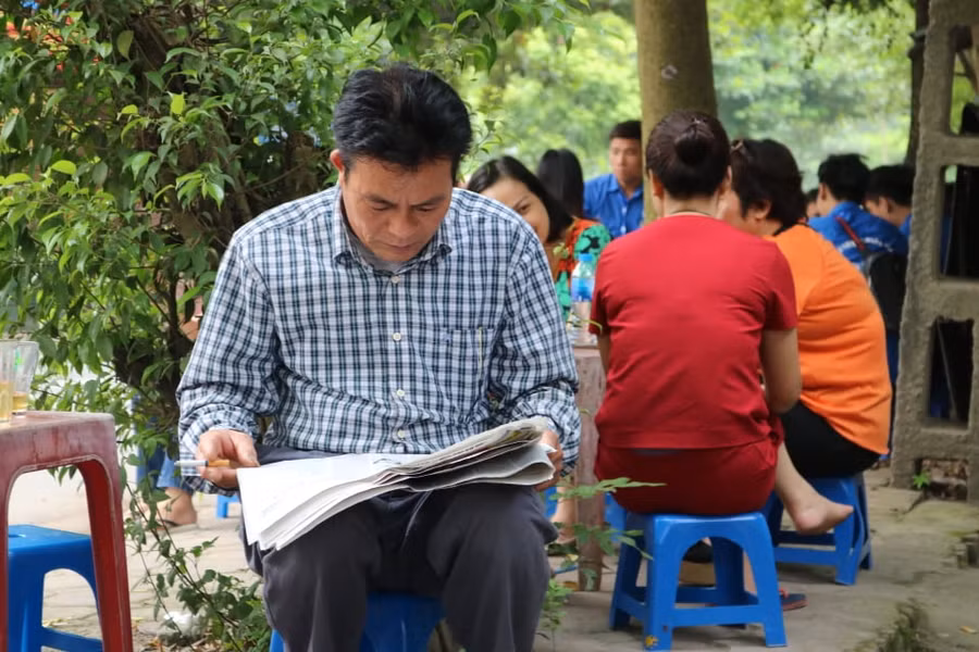 Trong thời gian chờ sĩ tử làm bài thi phụ huynh đọc báo "đốt thời gian".