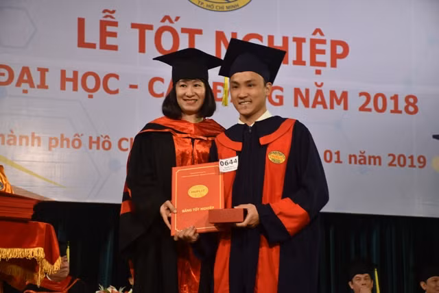 TS Trần Thanh Nhàn - Phó Hiệu trưởng Phụ trách điều hành trường (trái) trao bằng tốt nghiệp cho các tân cử nhân