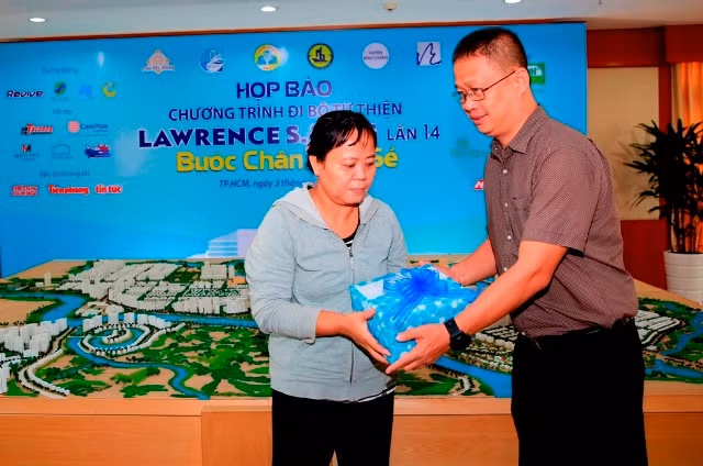 Tại buổi họp báo: Ông Vũ Xuân Đức (phải) tặng quà lưu niệm cho bà Phạm Thị Lên (Huyện Bình Chánh) - người đã vươn lên thoát nghèo nhờ sự hỗ trợ của Chương trình đi bộ Từ thiện Lawrence S. Ting 