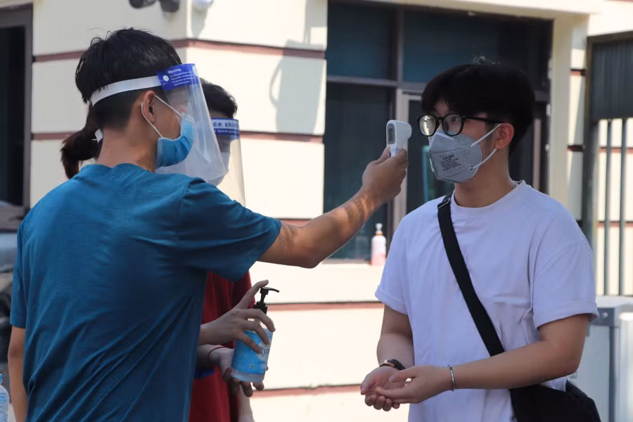 Thí sinh rửa tay sát khuẩn, đo thân nhiệt trước khi vào phòng làm thủ tục đăng ký thi.