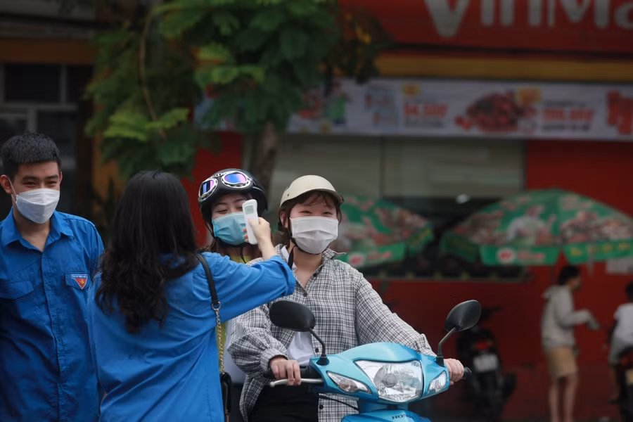 Lực lượng tình nguyện viên đo thân nhiệt cho thí sinh đến Điểm thi.