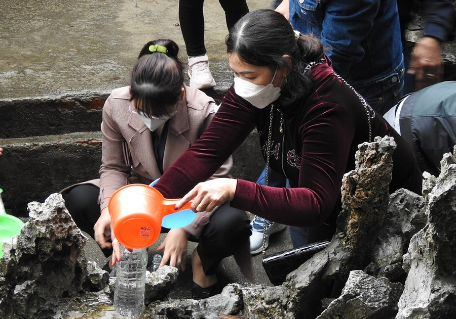 Du khách múc nước cho vào chai nhỏ để mang về.