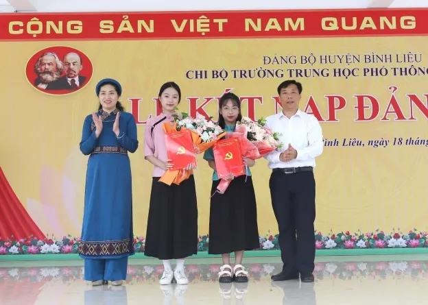 Bí thư Huyện ủy Bình Liêu và Hiệu trưởng Trường THPT Bình Liêu trao quyết định, tặng hoa chúc mừng 2 đảng viên mới.