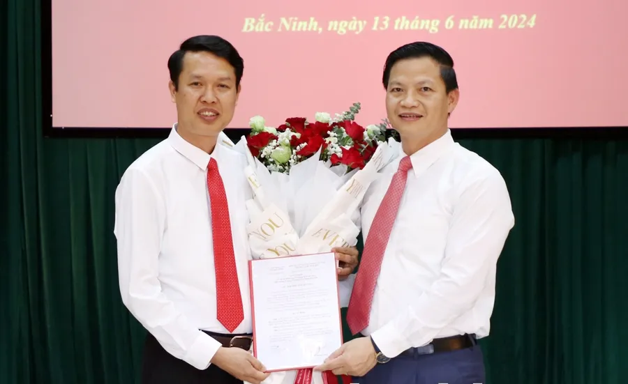 Phó Chủ tịch Thường trực UBND tỉnh Bắc Ninh- Vương Quốc Tuấn (bên phải) trao Quyết định và tặng hoa chúc mừng đồng chí Vũ Quang Khuê.