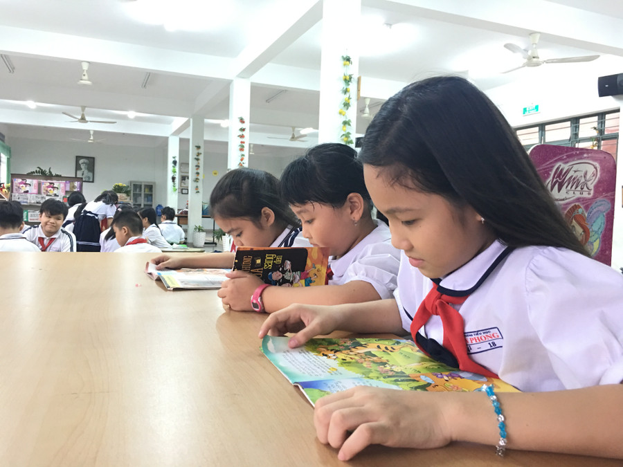 Em Bùi Yến Nghi (bìa phải), học sinh lớp 4/1, cho biết em rất thích được vào thư viện đọc sách. Sinh ra ở Bạc Liêu, nhưng Nghi phải cùng cha mẹ rời quê đi lập nghiệp tại khu vực chợ Bình Điền, Q.8, TPHCM cách đây 1 năm. Được biết, hiện tại trường An Phong đang tiếp nhận hơn 45% học sinh có hoàn cảnh như Nghi.