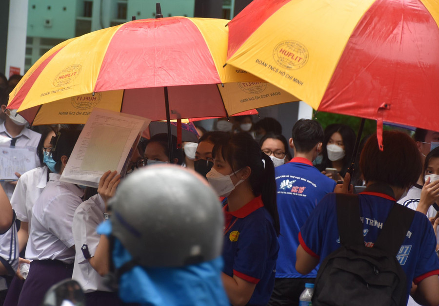 Các tình nguyện viên che dù cho thí sinh rời khởi điểm thi đến xe phụ huynh. Các tình nguyện viên che dù cho thí sinh rời khởi điểm thi đến xe phụ huynh.