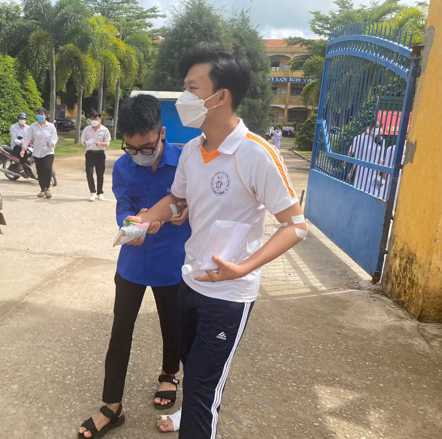 Một thí sinh đau chân tại điểm thi THPT Đông Thạnh (huyện Cần Giuộc, tỉnh Long An) được các TNV hỗ trợ.