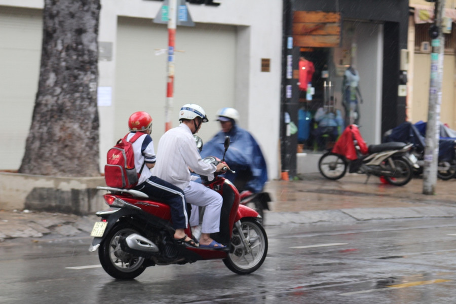 Một em học sinh co ro trong cơn mưa do bão Tembin sáng nay