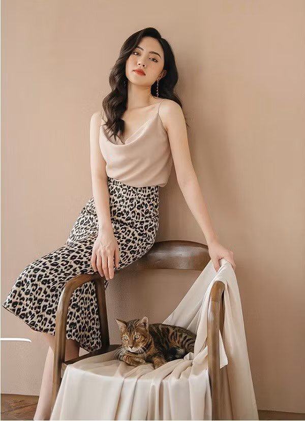 Chị em hãy mix áo hai dây cổ đổ với chân váy suông dáng midi để bảo toàn hình ảnh thanh lịch, nhã nhặn.