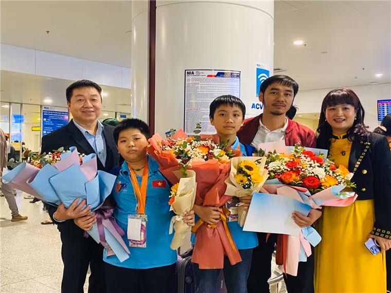 Em Trịnh Lê Hưng (thứ 3 từ trái sang) được thầy giáo chủ nhiệm và các bác phụ huynh đón tại sân bay Nội Bài sau cuộc thi Toán ITMC tại Thái Lan.