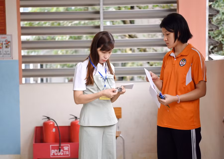 Giám thị kiểm tra đồng hồ của thí sinh trước giờ vào phòng thi.