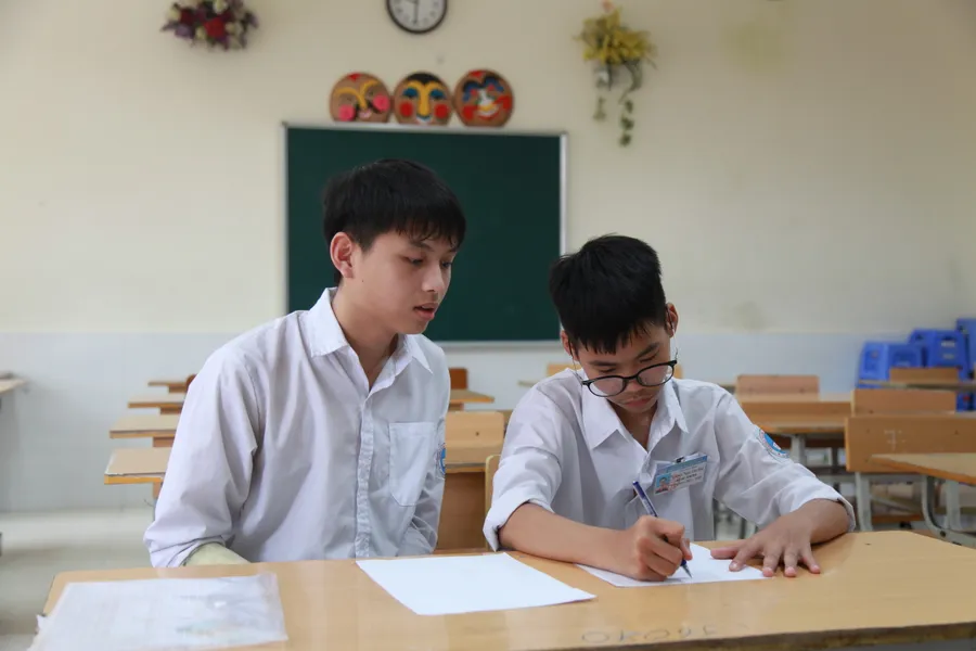 Thí sinh bị gãy tay cần người hỗ trợ chép bài tại điểm thi Trường THCS Trần Phú (quận Hoàng Mai).