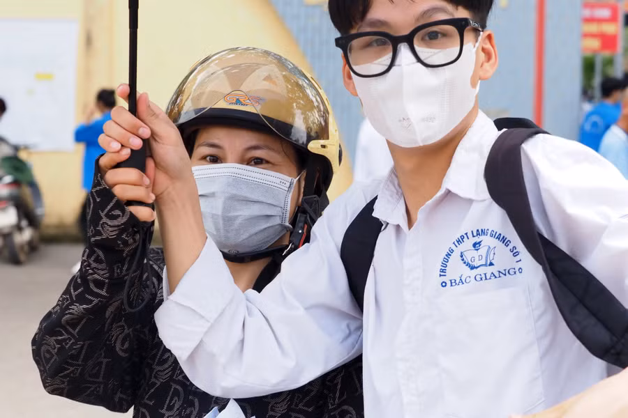 Mẹ che ô động viên con trai trong kỳ thi.