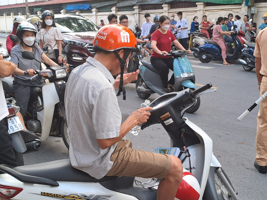 Anh Võ Văn Hân (trú tại phường Đình Bảng, Từ Sơn) tranh thủ uống thuốc, sau khi đưa con đến điểm thi.