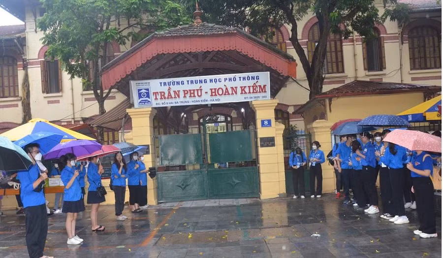 Sinh viên tình nguyện đội mưa chờ thí sinh. Ảnh Phạm Hiền.