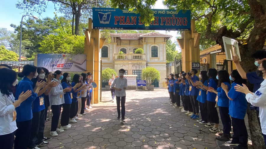 Tình nguyện viên xếp hàng vỗ tay, chúc mừng thí sinh hoàn thành bài thi.