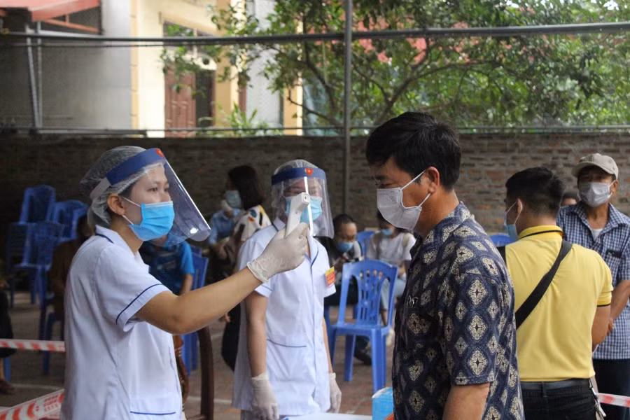 Lực lượng y tế kiểm tra thân nhiệt cho người dân phồng dịch Covid-19.