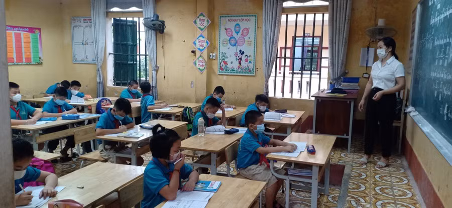 Học sinh đeo khẩu trang, ngồi giãn cách trong lớp học.