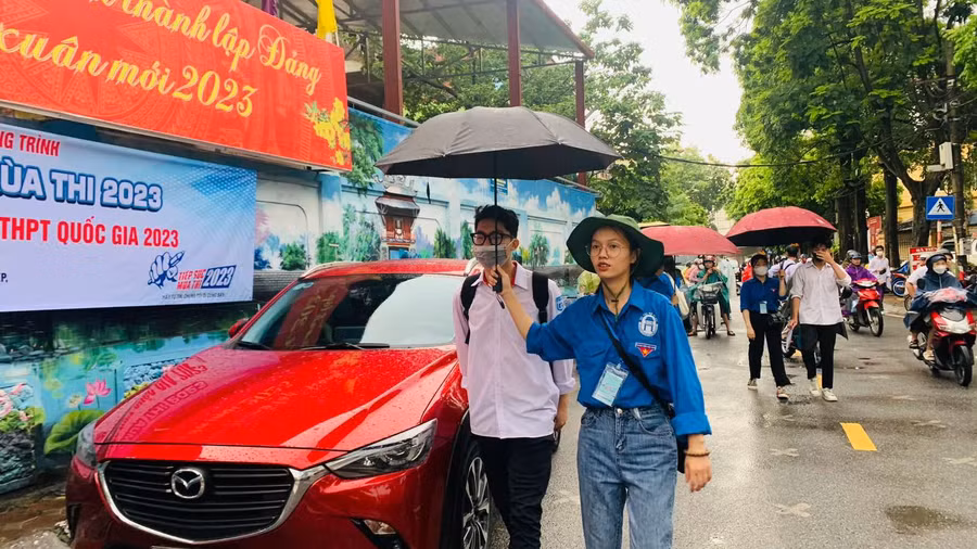 Lực lượng tình nguyện che ô hỗ trợ thí sinh tại điểm thi.