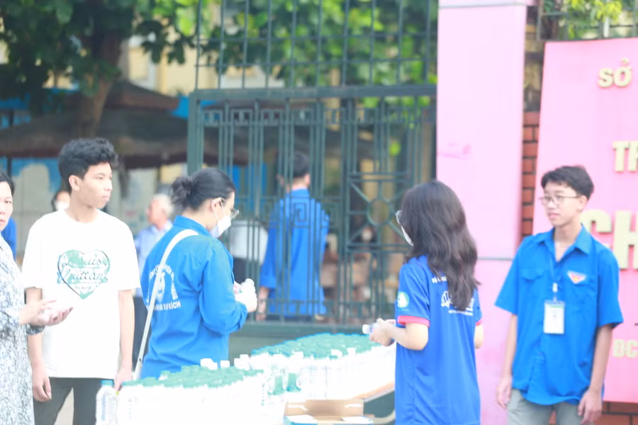 Thanh niên tình nguyện tặng nước uống và động viên thí sinh tại khu vực cổng trường thi.