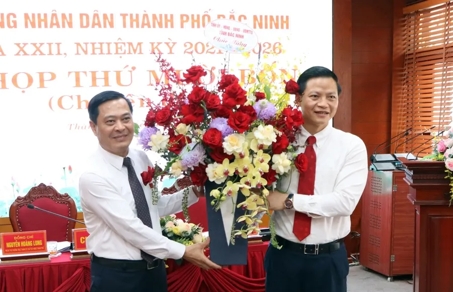 Ông Vương Quốc Tuấn - Phó Chủ tịch Thường trực UBND tỉnh Bắc Ninh (bên phải) tặng hoa chúc mừng tân Chủ tịch UBND TP Bắc Ninh Nguyễn Mạnh Hiếu.