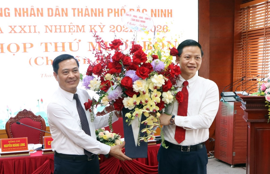 Ông Vương Quốc Tuấn - Phó Chủ tịch Thường trực UBND tỉnh Bắc Ninh (bên phải) tặng hoa chúc mừng tân Chủ tịch UBND TP Bắc Ninh Nguyễn Mạnh Hiếu.