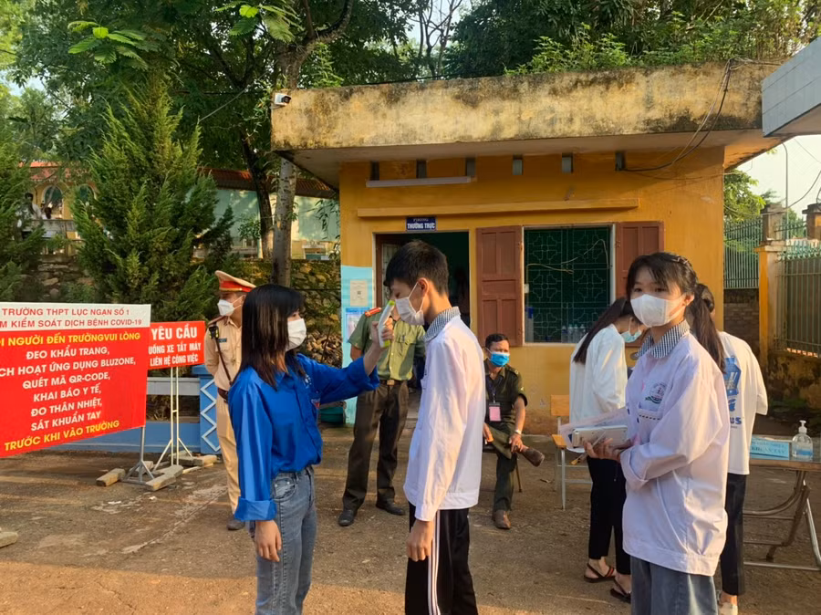Lực lượng tình nguyện đo thân nhiệt, hỗ trợ thí sinh trong kì thi diễn ra mùa dịch tại điểm thi Trường THPT Lục Ngạn số 1.