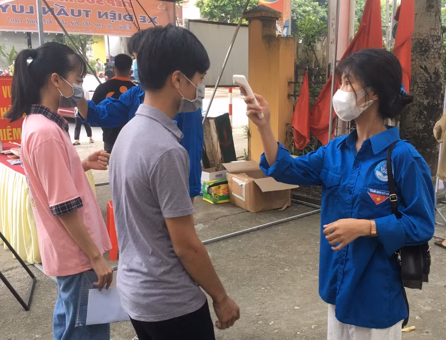 Thanh niên tình nguyện hỗ trợ thí sinh kiểm tra thân nhiệt.