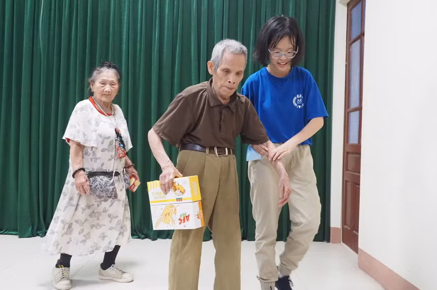 Học sinh trường THCS Mai Dịch (áo xanh) đỡ cụ ông tại buổi lễ trao quà.