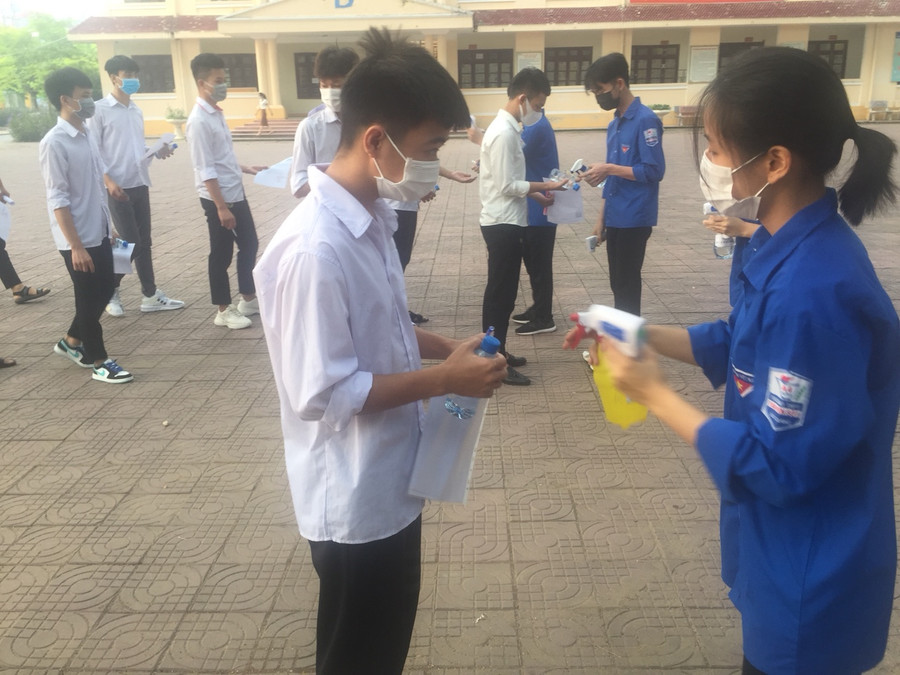 Thanh niên tình nguyện đo thân nhiệt, động viên thí sinh làm bài thi tốt nhất.