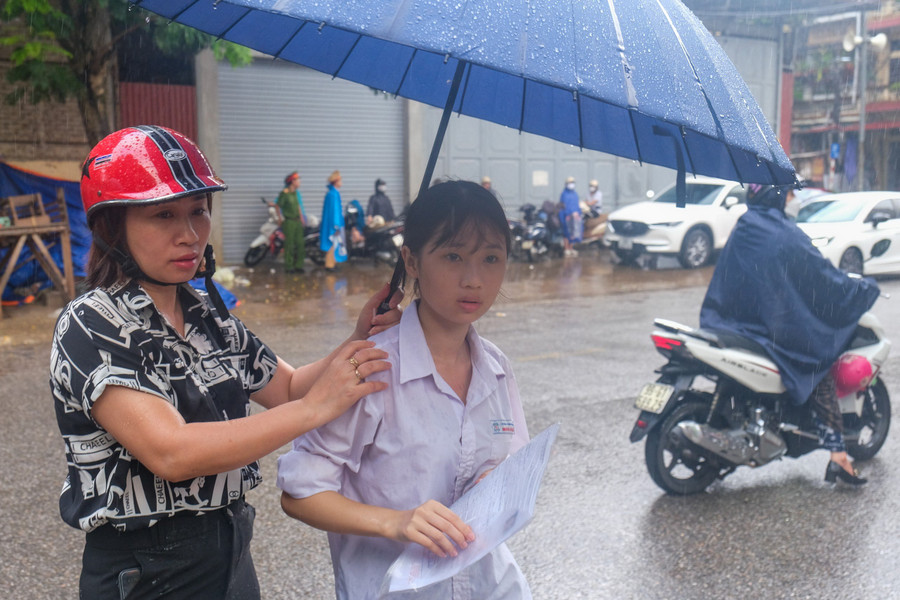 Hỗ trợ thí sinh di chuyển dưới cơn mưa.