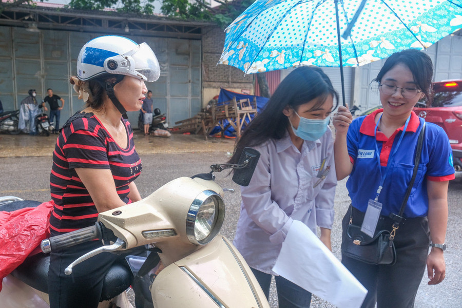 Tình nguyện viên hỗ trợ thí sinh ngay tại khu vực cổng trường thi.