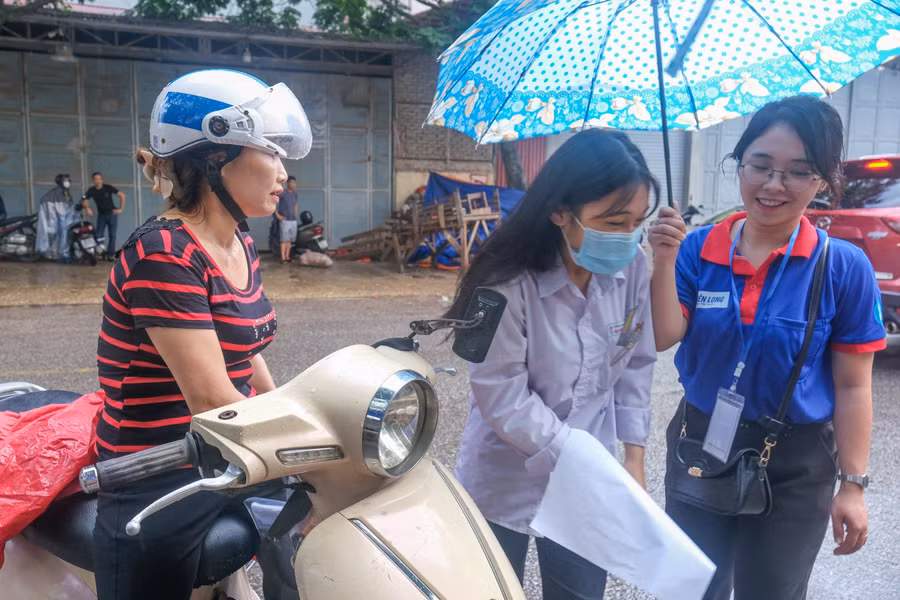 Tình nguyện viên hỗ trợ thí sinh ngay tại khu vực cổng trường thi.