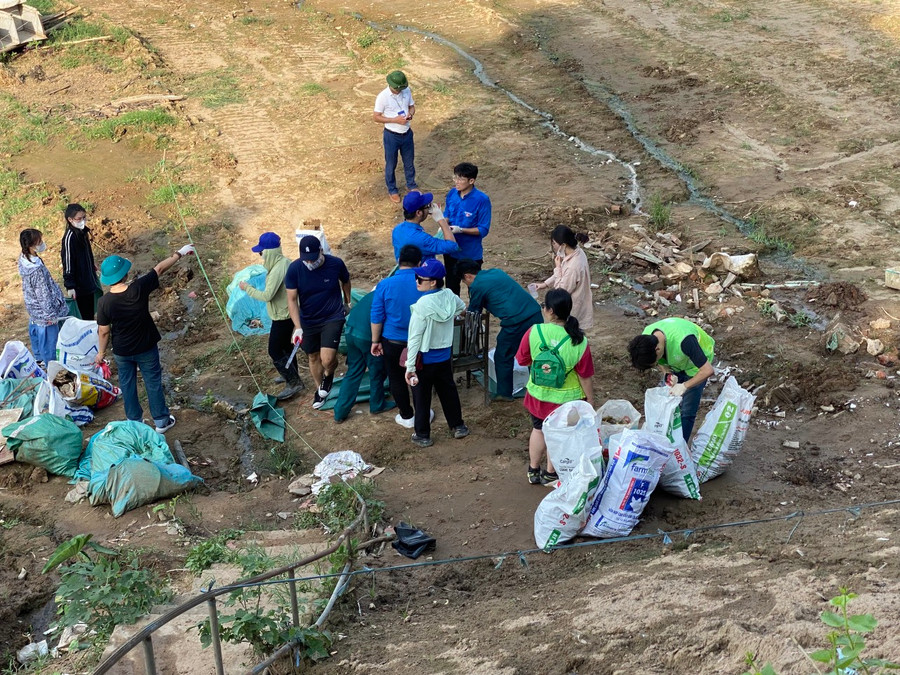 Hình ảnh tình nguyện viên dọn dẹp, thu gom rác khu vực vừa được giải tỏa ven bờ sông Hồng.
