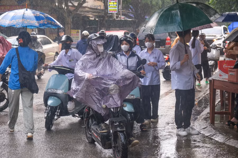 Mưa to khiến nhiều thí sinh vất vả trong việc di chuyển, tình nguyện viên đón thí sinh vào điểm thi.