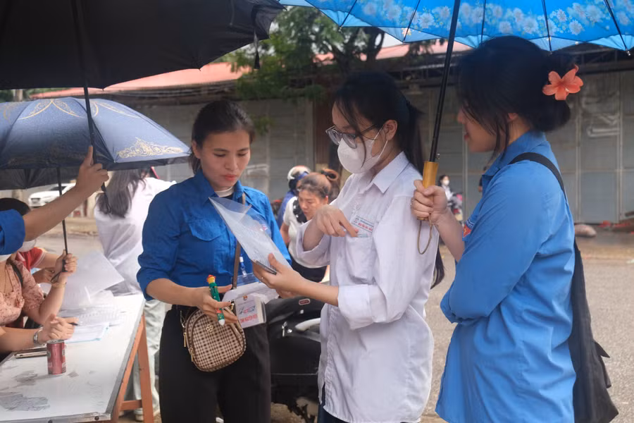 Lực lượng tình nguyện viên hỗ trợ thí sinh dưới cơn mưa sáng 27/6.