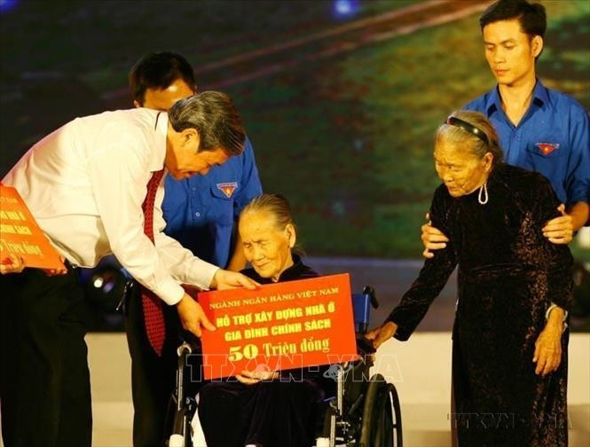 Trưởng Ban Tuyên giáo Trung ương Đinh Thế Huynh trao tiền hỗ trợ xây dựng nhà ở cho gia đình chính sách trong Chương trình an sinh xã hội &quot;Hùng thiêng đất mẹ&quot; (Quảng Trị, 18/7/2015). Ảnh: Hồ Cầu/TTXVN