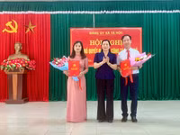 Bà Cầm Thị Khay (đứng giữa) trao quyết định và tặng hoa chúc mừng ông Ngô Văn Bích và bà Đào Thị Xuân.