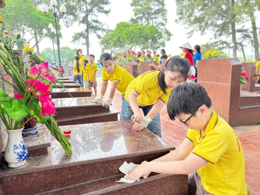 Các em học sinh trường Tiểu học Đinh Tiên Hoàng chăm sóc phần mộ các liệt sĩ. dinh-tien-hoang.jpg
