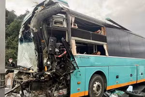 Phần đầu xe khách 50H-302.xx bị hư hỏng nặng sau cú va chạm, nhiều mảnh vỡ kính lái rơi vãi trên mặt đường.