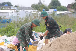 Bộ đội xúc cát vào bao để gia cố bờ kè An Lương. 